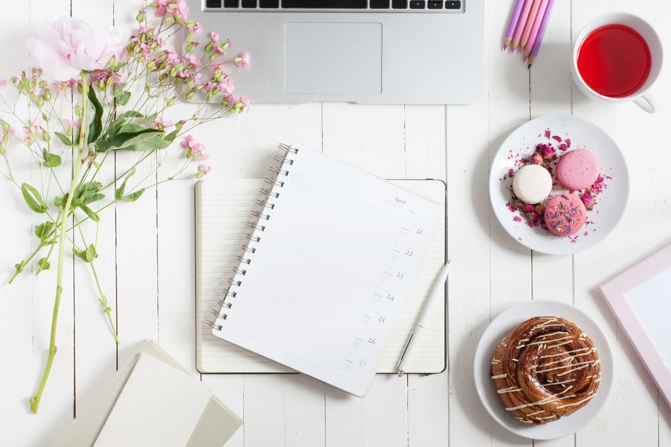 Escritorio de wedding planner con portátil, libreta y flores