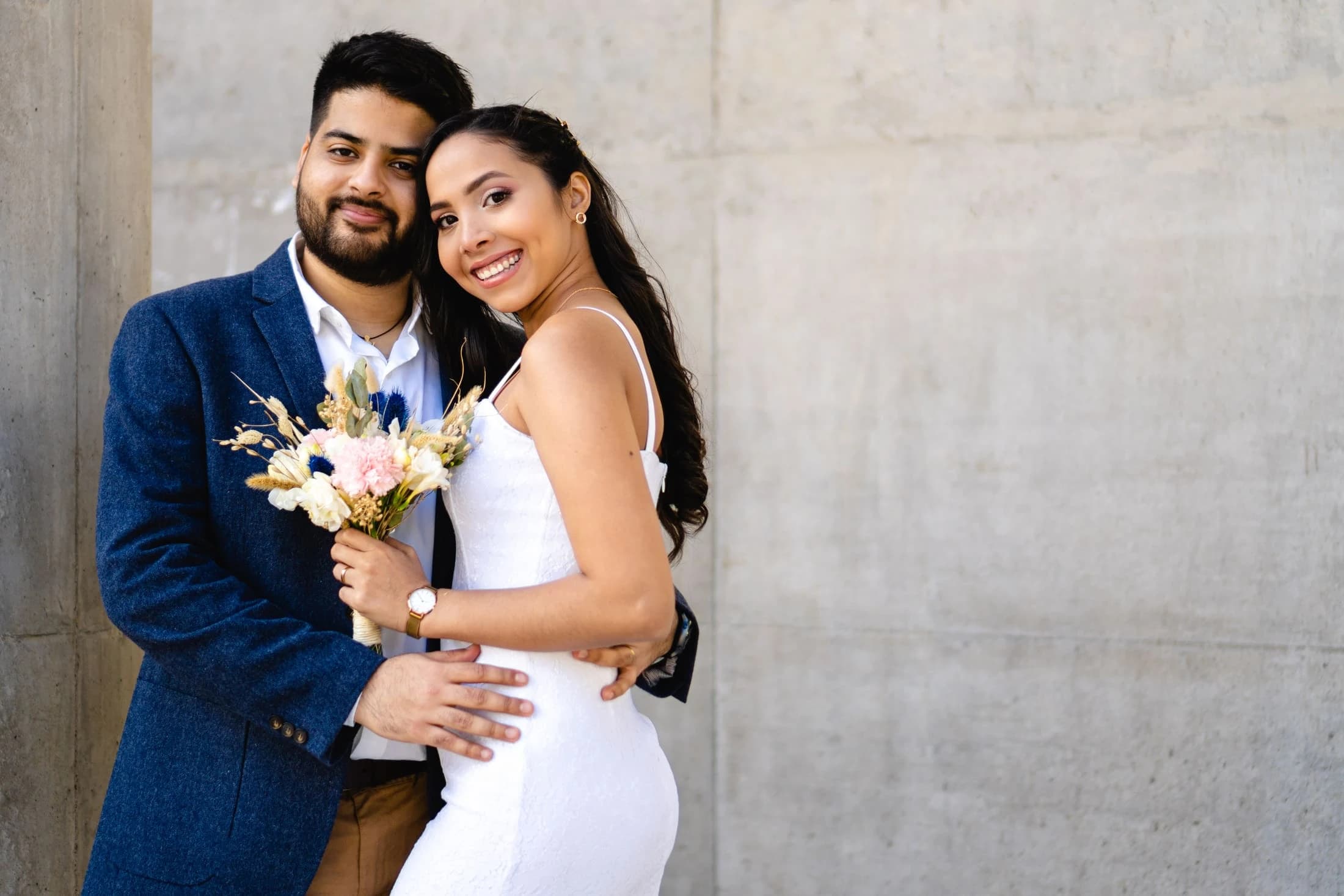 Novios con ramo de flores mirando a cámara